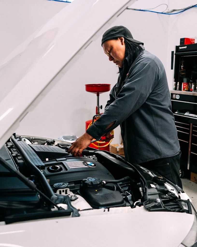 Technician working in a white BMW engine bay